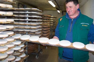 A young farmer proudly displays his newest crop of Reblochon cheese, used in several regional dishes.