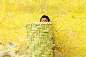 A Mayan youngster hides behind a market basket.