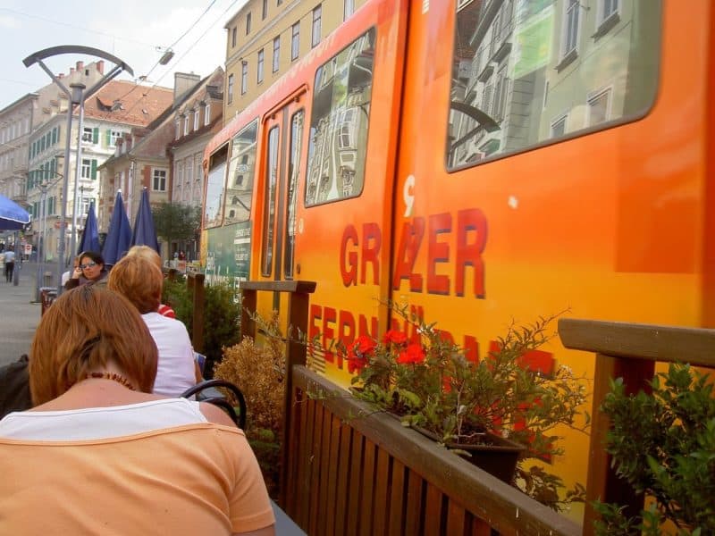 The tram is right next to the sidewalk in downtown Graz.