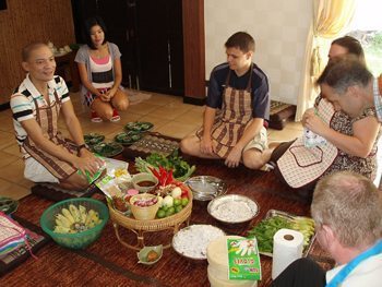 The group gathers around the fresh ingredients from the market at Bangkok Cooking Academy.