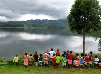 Primary school children eat a breakfast of plain porridge while looking out over the waters of Lake Bunyoni.