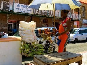 A woman cooks sweet corn in a street stand made of a shopping cart in Saint Georges.