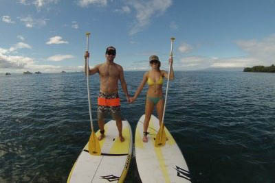 A couple holds hands while stand up paddle boarding. Maui Stand Up Paddle Boarding photos.
