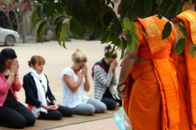Participants kneel before monks in Cambodia.
