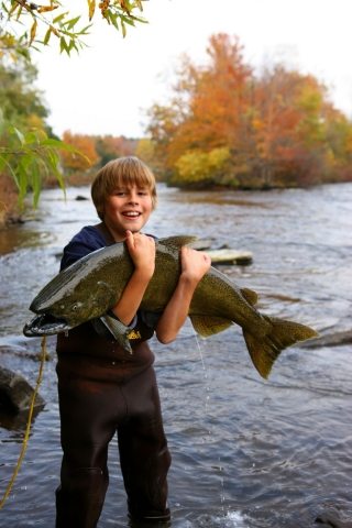 Thousand Islands has a dedicated fishing community -- a young boy holding a large salmon on the Salmon River in Pulaski in Oswego County! Oswego County Dept. of Tourism Photos.