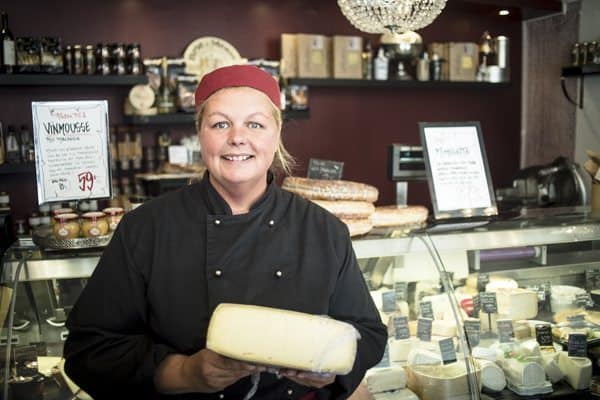 Vera stands with local cheese at her downtown store in Gothenburg.