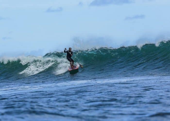 Titus Kinimaka slices across a wave face on his stand up paddle board in Hanalei Bay Kauai HI. Photo by Ry Cowan