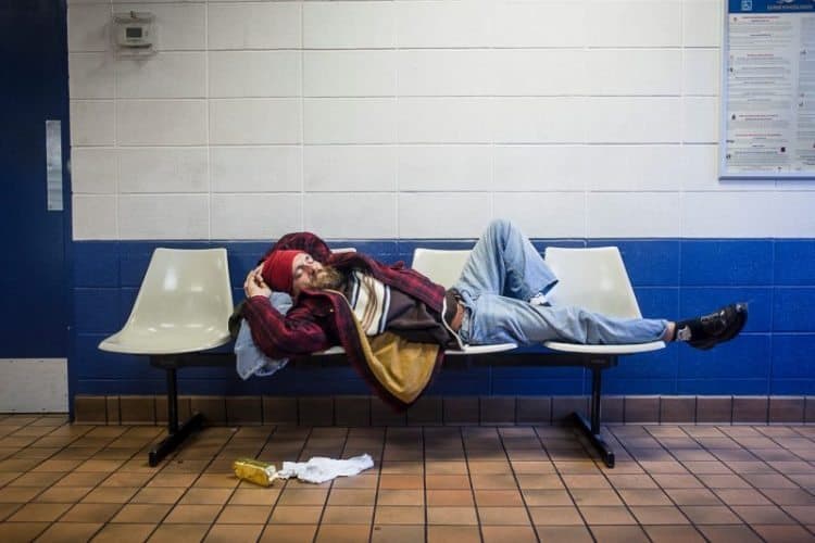 A man sleeps on a bench in a bus station, somewhere in the United States.