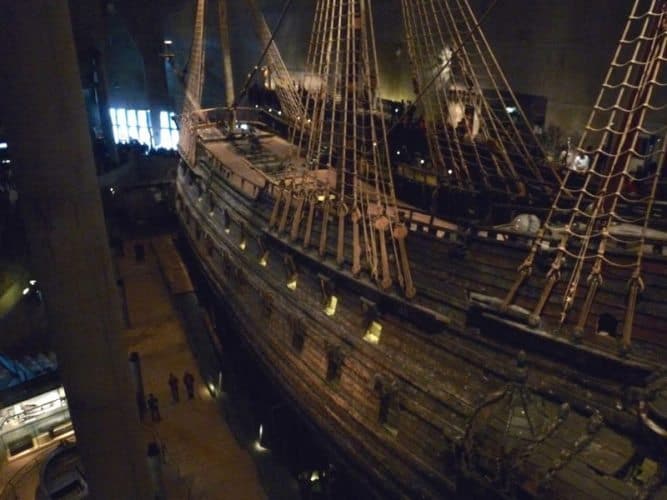 The massive Vasa, a ship recovered after it sank in the harbor, dwarfs mere mortals beside it.