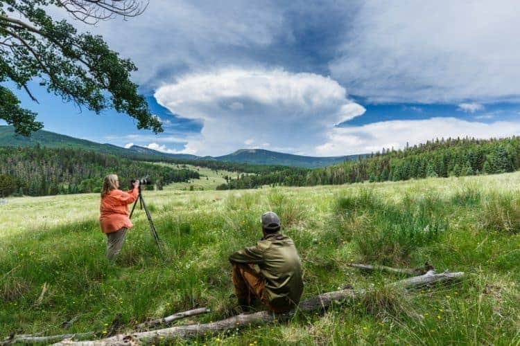 A photographer shooting in a meadow as cumulonimbus capillatus clouds form over Vermejo Park Ranch, New Mexico. James Reidy photos