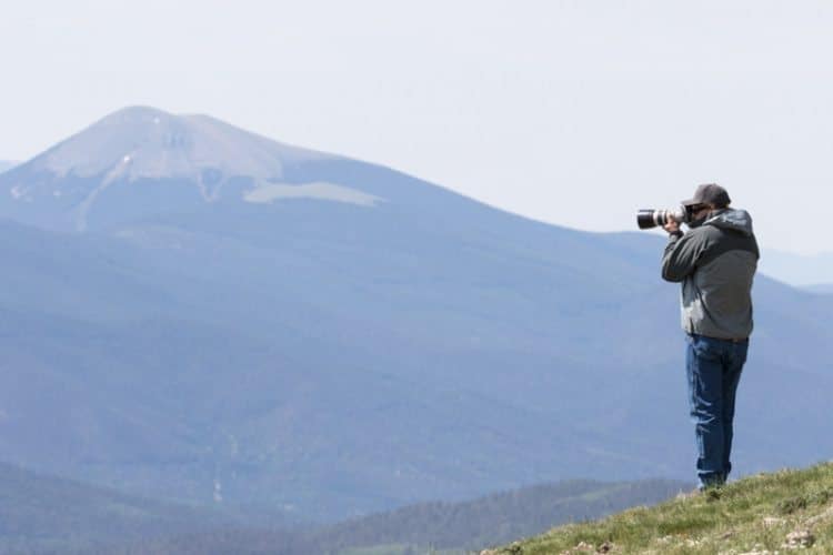 Photographer on ridge above timberline looking into valleys below at East Fork overlook, Vermejo Park Ranch, Colorado, USA. Overlook is in Colorado, but most of Vermejo is in New Mexico