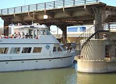 A sightseeing boat passes under a drawbridge.