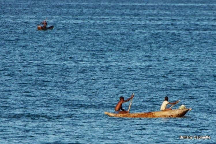 Local boys paddling out to better fishing territory on their hand-carved wooden pirogue.