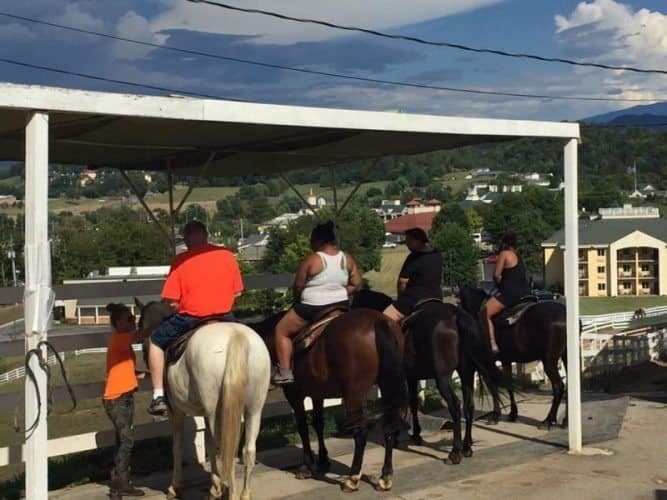 Tourists saddle up for a trail ride at the Five Oaks Riding Stable in Sevierville, TN