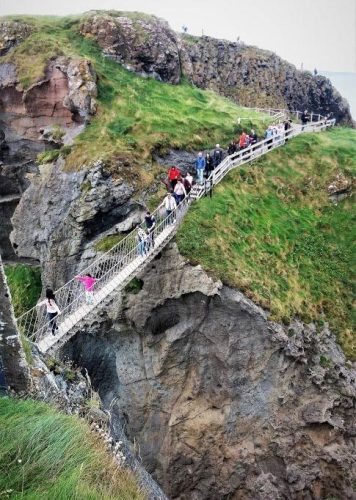 A daring group of tourists brave the Carrick-a-Rede Rope Bridge on this windy 