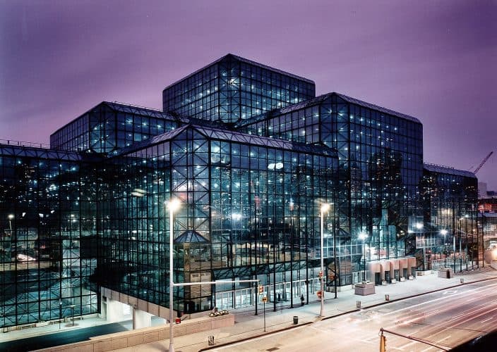 A Phenominal view of the Jacob J. Javits Convention Center as its clear glass strcture illuminates the sky at dusk.