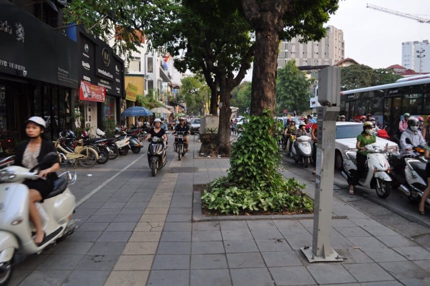 In Hanoi, the sidewalk is no place to hide from the onslaught of motorbikes.