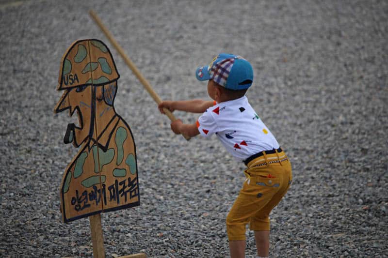 Children hitting these wooden cutouts of U.S. Army soldiers with sticks. 