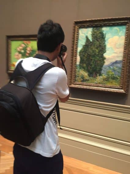 A man takes a photo of a van Gogh in the Metropolitan Museum of Art, New York City