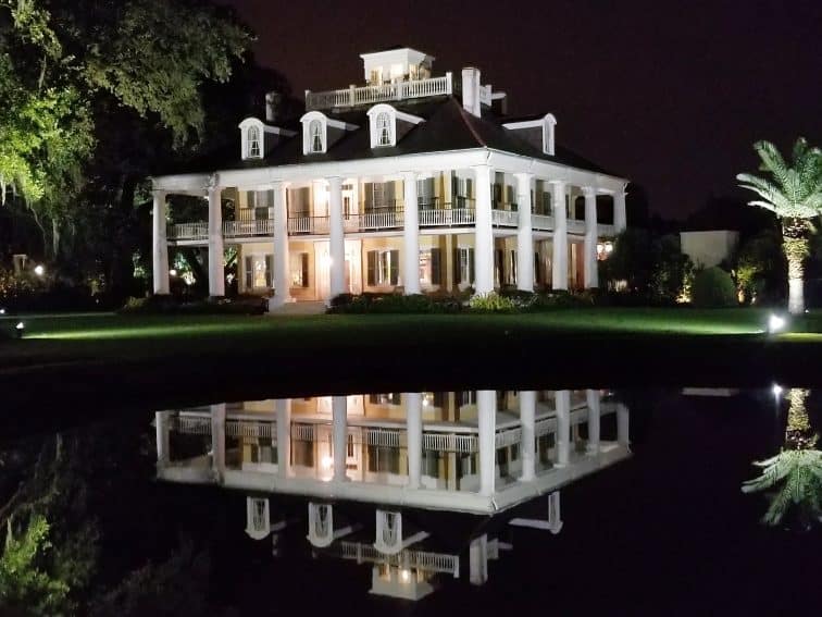 Houmas House by night, as reflected in the pond near the oak-lined entrance to this historic plantation house. | GoNOMAD Travel
