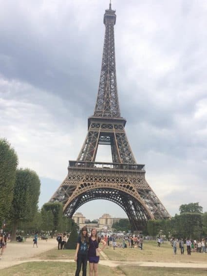 Sarah Eddy (left) and sister Becca Eddy in front of the Eiffel Tower smartphone in hand.