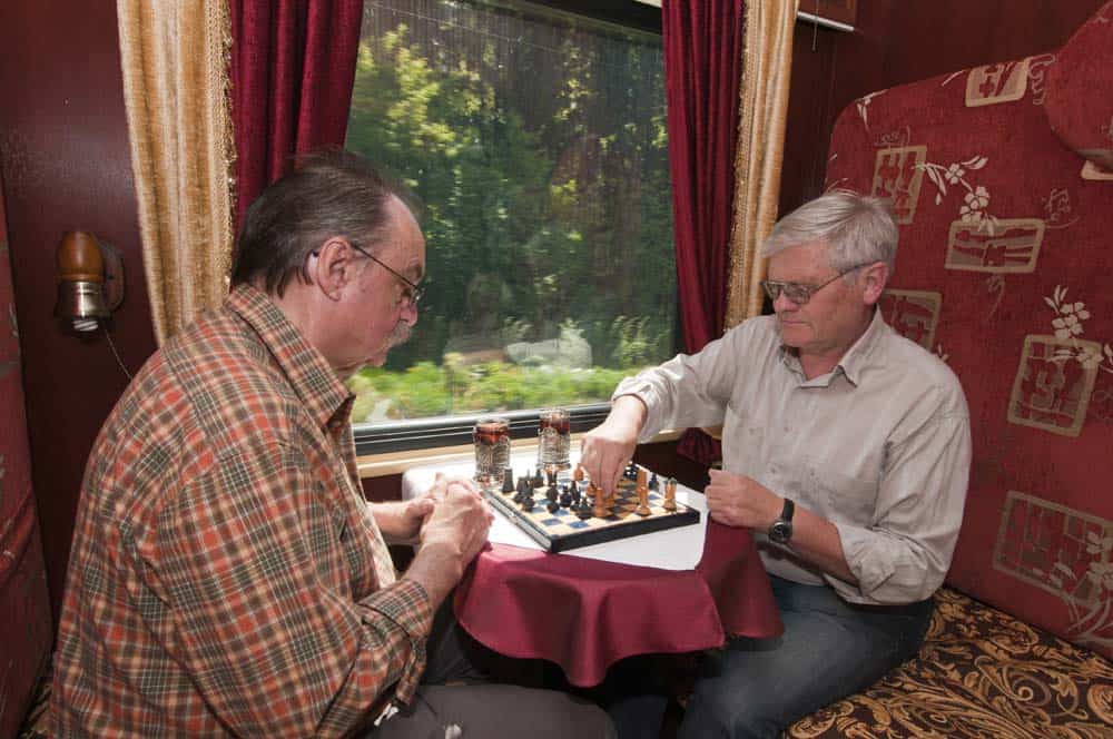 Two men playing chess as they ride the train to their next destination.