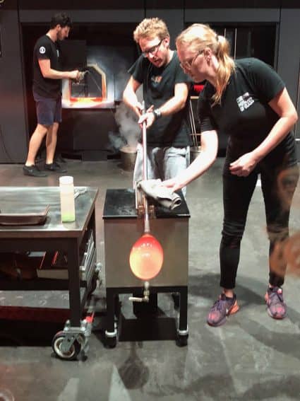 Glassblowing artists at the Corning Museum of Glass in Corning, NY craft a piece in front of an audience. 