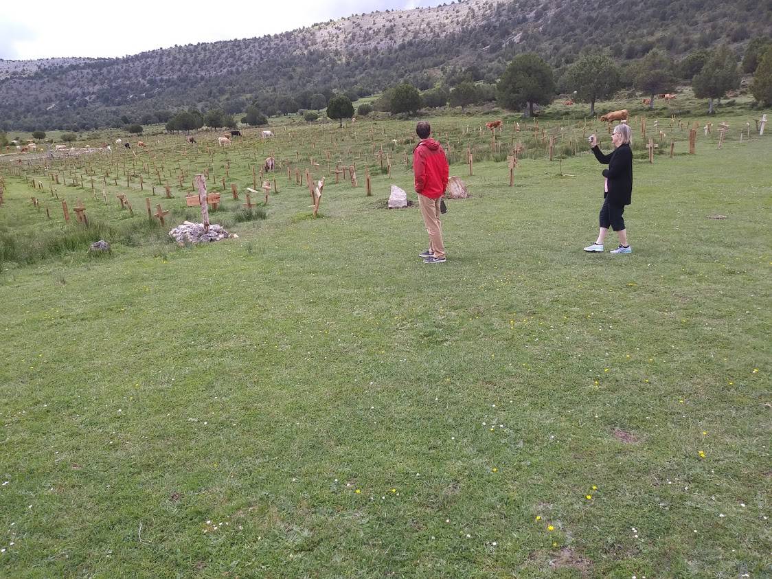 Tourists snap pictures of the restored Sad Hill Cemetery as cows roam the open field.