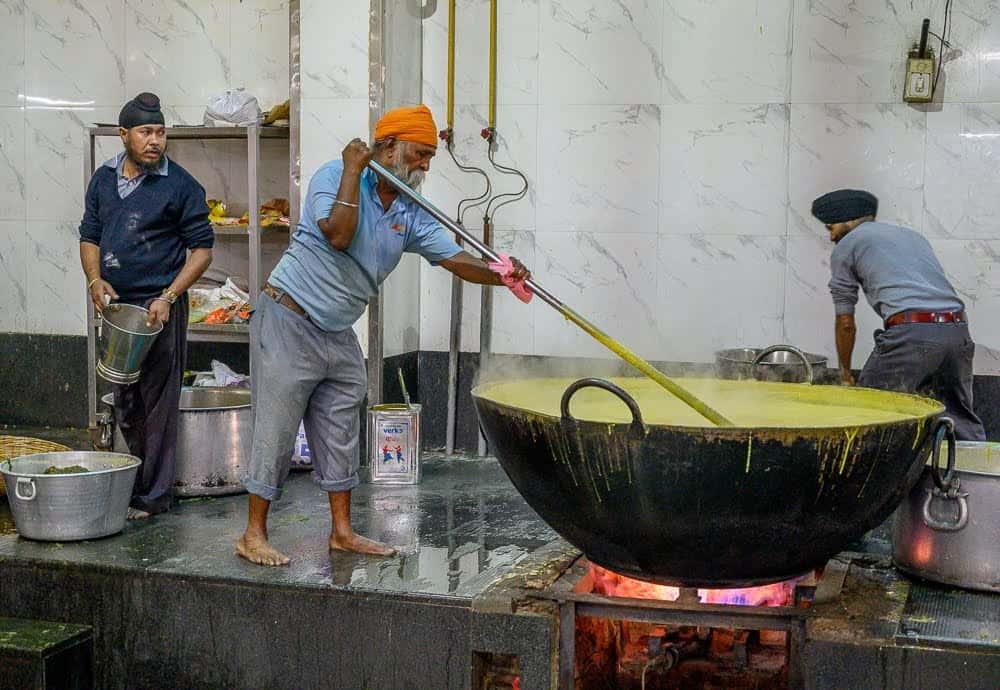 It is challenging work cooking in massive woks while standing barefoot on the hot surface atop the cooking platform.