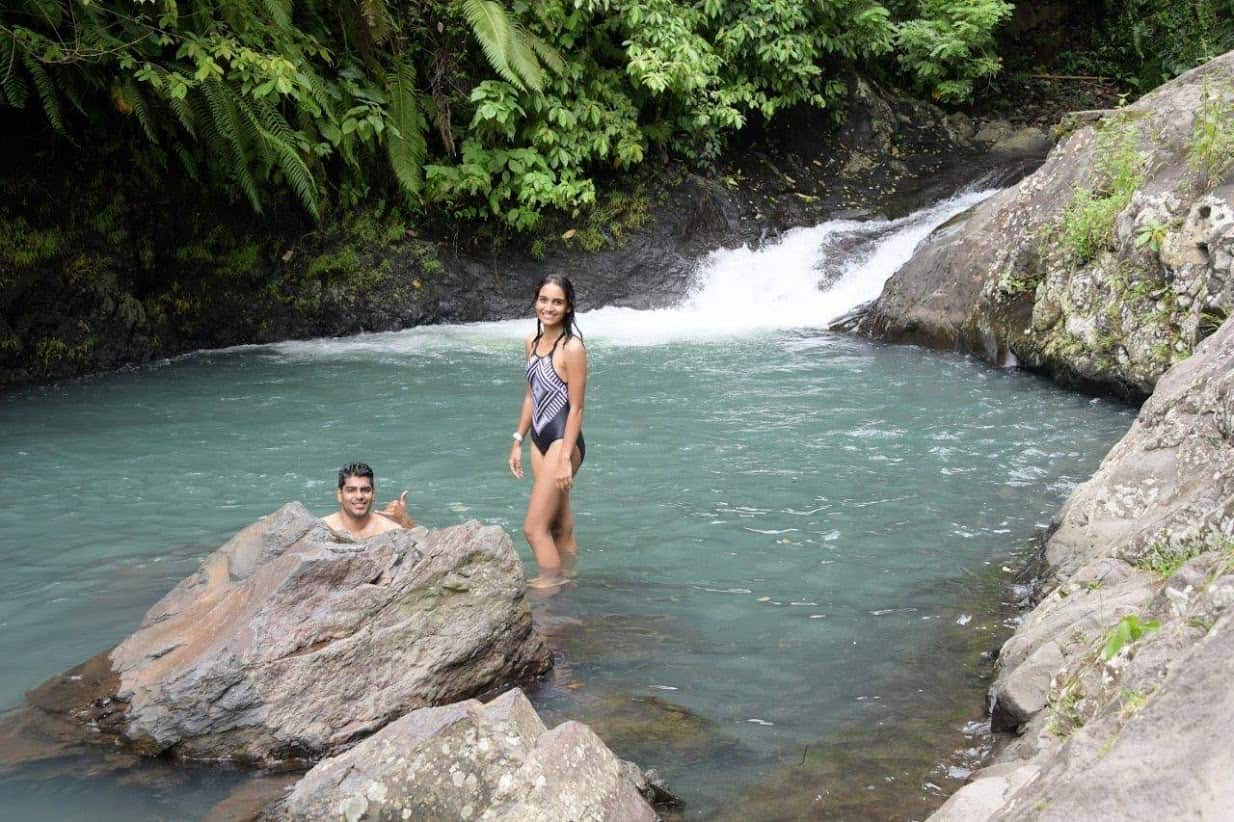 Young couple swimming between the falls at Sambangan Secret Garden Waterfalls