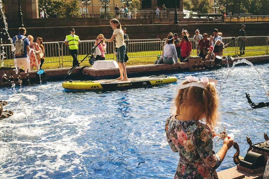 Children stand up paddle in a shallow pool set up for Moscow City Day.