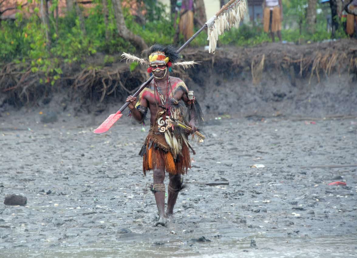 Traditionally dressed Asmat walks to his canoe. Tab Hauser photos