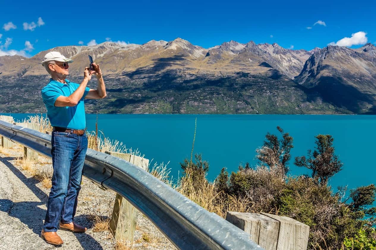 Senior Nomads: David taking a photo with his phone beside Lake Wakatipu