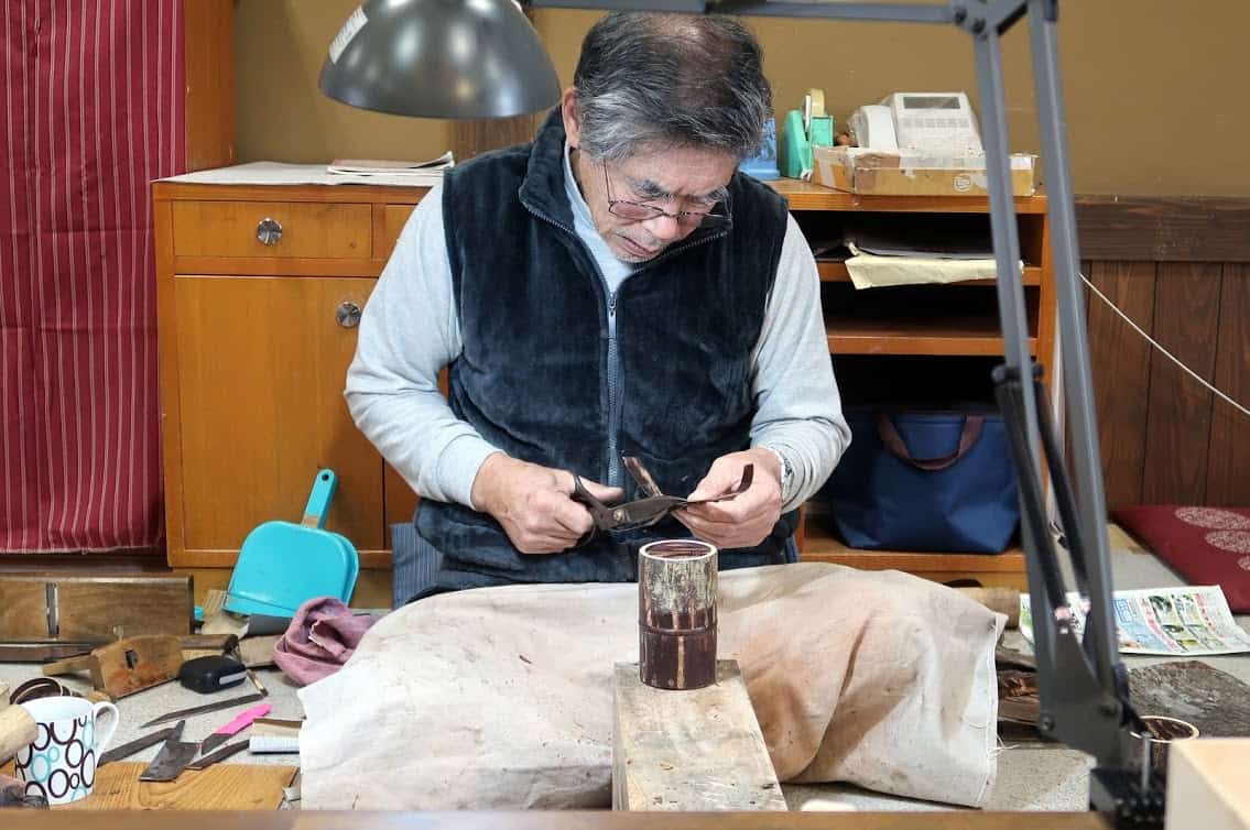 A craftsman works his trade in kabazaiku, applying strips of cherry bark to tea canisters and other products at Kakunodate Denshokan