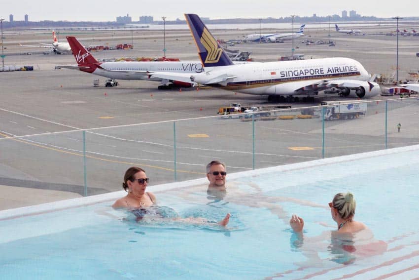 Guests wade in the heated rooftop pool with a Singapore Airlines A380 in view.