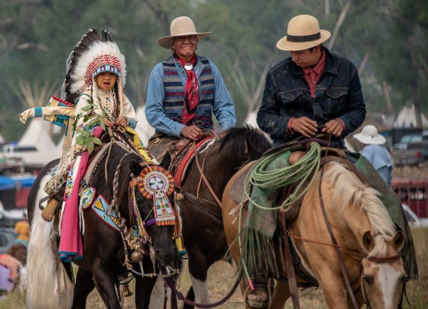 Young riders in the Crow Fair parade will have an elder riding with them for safety reasons. In this photo, three generations of a Crow family take part in this time-honored tradition.