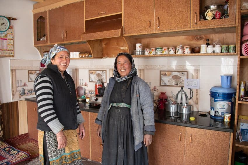 Tensin's mother and auntie stand in the kitchen/main room of their simple dwelling. Like most locals, they wear cold-weather clothing both indoors and outside.
