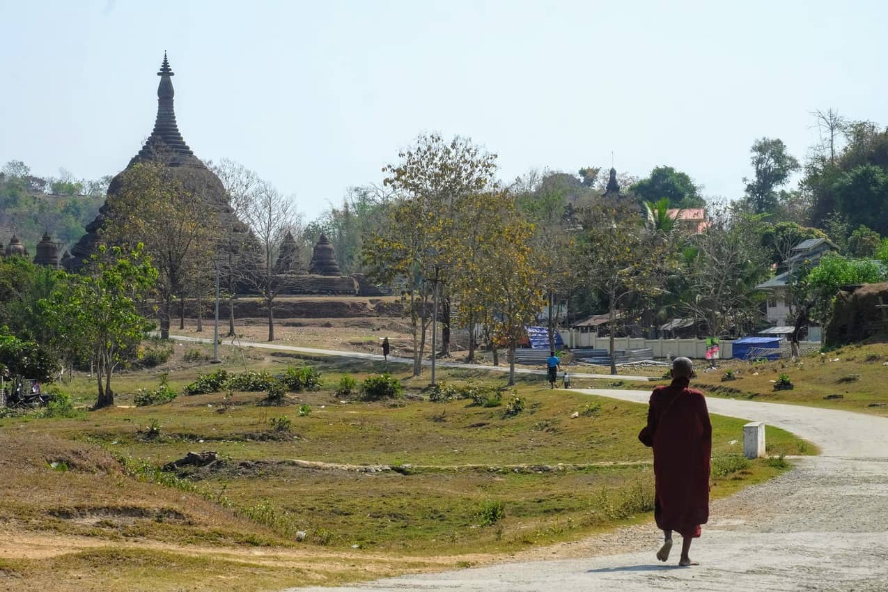 A monk wanders past the northern temples with faint gunfire in the background