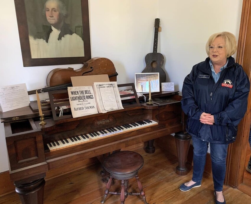 Linda Faust stands by the Rosewood piano used by the Duclon brothers in their family band.