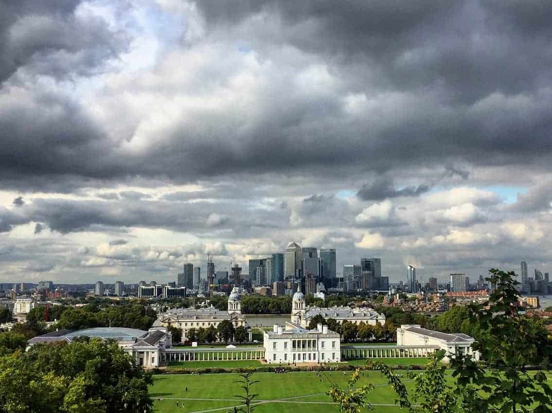 The National Maritime Museum in Greenwich, England with London skyline in the background. The photo is taken from the Greenwich Mean Time Observatory which shares the park with the Maritime Museum