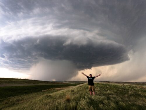 Erik Burns posing with a large tornadic supercell in extreme western North Dakota during Tour 6 2021
