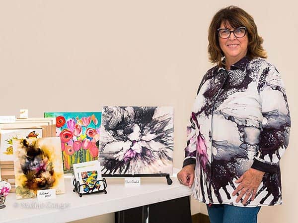 Artist Marcia Breznay stands with her artwork that has been adapted to an apparel line. Photo by Kathy Condon