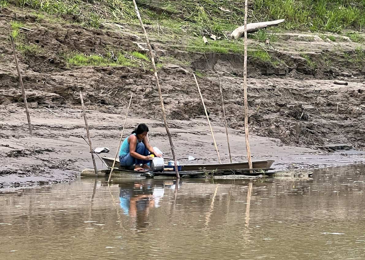 A woman washing cookware in the Amazon