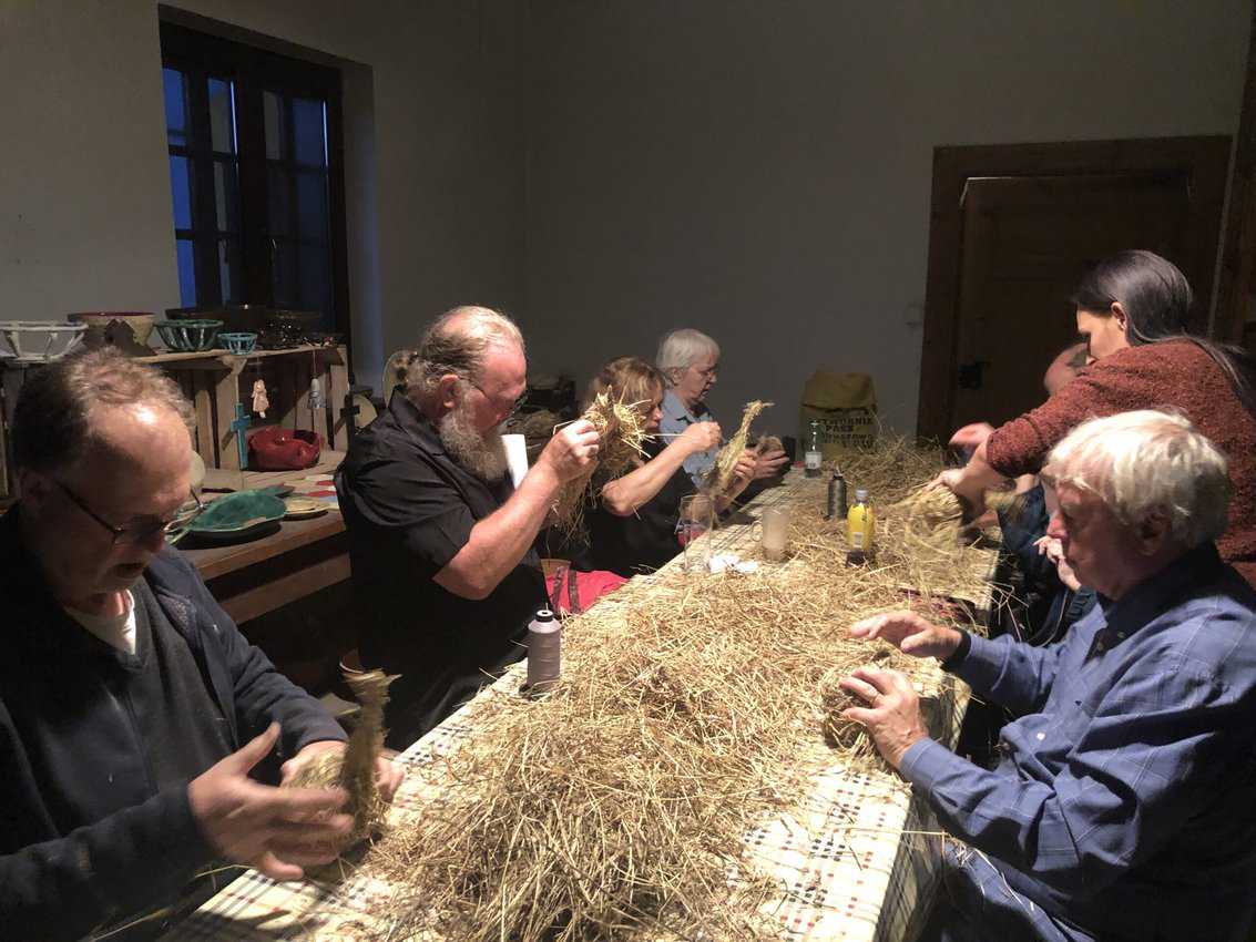 A group of Americans is participating in a workshop to learn how to make hay ornaments
