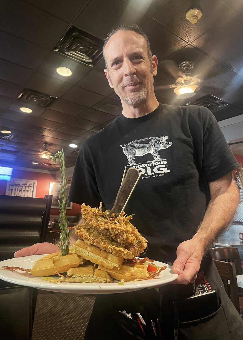  A server delivers chicken and waffles to the table at Hash House A Go Go.
