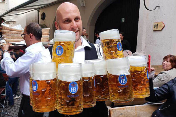 Professional waiters delivering tankards of beer.